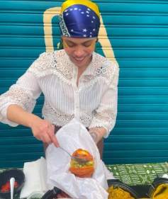 Cozinheira de lenço colorido preparando um sanduíche diante da porta turquesa